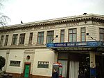 A tan-coloured building with brown-framed windows and a sign reading "METROPOLITAN EDGWARE ROAD STATION RAILWAY" in brown letters