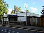 A brown-bricked building with a rectangular, dark blue sign reading "ICKENHAM STATION" in white letters all under a light blue sky