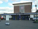 A red-bricked building with a rectangular, dark blue sign reading "NORTHFIELDS STATION" in white letters all under a light blue sky