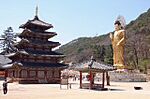Buddhist temple with a large golden statue in a mountain setting