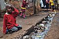A young boy sits over an open sewer in the Kibera slum, Nairobi