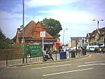 A red-bricked building with a rectangular, dark blue sign reading "SOUTHFIELDS STATION" in white letters all under a blue sky