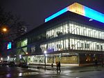 Exterior facade of The Image Centre at night, with blue and yellow lights illuminating the top portion of the building