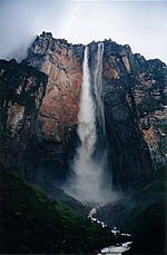 A very tall waterfall in tropical setting