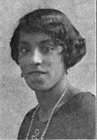 A young African-American woman, with dark hair cut into a 1920s bob, wearing drop earrings and a strand of pearls.