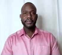 Annan wears a pink button up shirt. He has closely shaven hair and a beard.