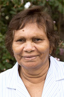 A smiling woman in a blouse who is facing the camera.