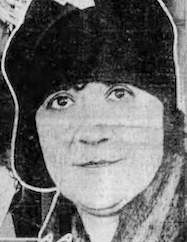 A woman with fair skin, wearing a dark cloche hat low over her forehead