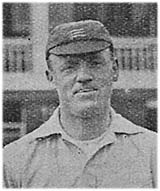 A black and white grainy image of the head and shoulders of a man. He is wearing a flat cricket cap, with three light horizontal swords visible, and a white top.