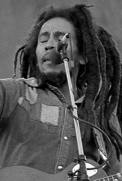 Black and white image of Bob Marley on stage with a guitar