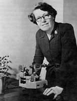 Photo of Helen Megaw, wearing glasses and leaning over a piece of lab equipment