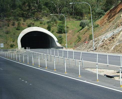 Road leading out of the black opening of a tunnel