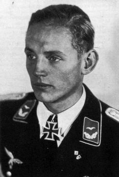 A black and white photograph of a young man wearing a military uniform looking off to the left wearing a neck order in shape of an Iron Cross.