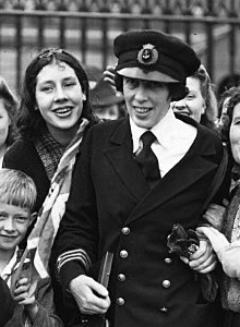 Black and white photograph of Victoria Drummond on receiving her MBE. She is wearing a naval uniform and surrounded by women and children.