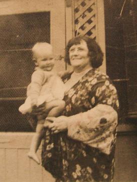 Old snapshot of Farrell. She is a plump smiling woman of 60, wearing a floral kimono and holding a toddler.