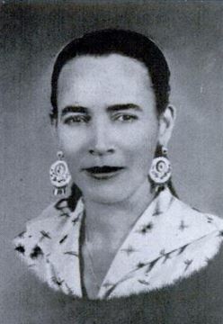 Black and white portrait of an Afro-Puerto Rican woman wearing large, round, dangling earrings and dressed in a pale colored, collared shirt, with geometric figures and birds.