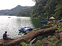 Man sitting on a fallen tree trunk near the wooden piers at Lake Balinsasayao.jpg