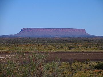 Photo of a wide, flat-topped plateau across the horizon, rising from surrounding scrubland