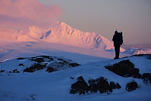 A hunter at sunrise on Adak, with Mt. Moffett in the background. Adak Island, Aleutian Islands, Alaska