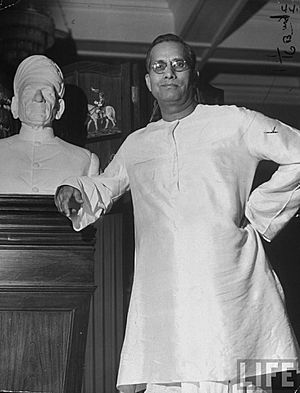 G. D. Birl, posing next to a bust of his father, at his palacial home in 1946