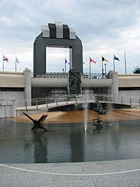 Tall arch in background, pool with statues of soldiers in foreground