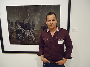Artist Werner Segarra standing in front of one of his photographic works with reflections of museum guests in reflection