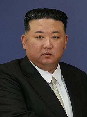 Photograph of Kim wearing a black suit jacket, a white shirt, and a white cream necktie.