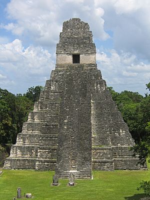 a steep-sided, stepped pyramid with a central staircase that rises from a flat, grassy area to a temple doorway at the top