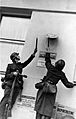Photo of two German soldiers removing Polish government insignia from a wall.