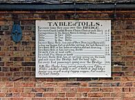 Antique table of bridge tolls now displayed on the outside of the toll house. Tolls range from a halfpenny for a pedestrian to two shillings for a large coach