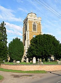 The stone tower of a church with a battlemented parapet and a truncated spire