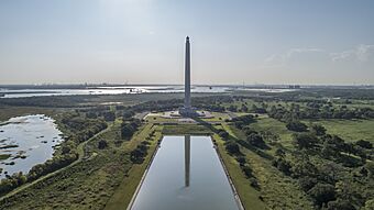 A tall monument with a star at the top in front of a reflection pool