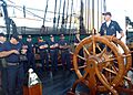 US Navy 050823-N-9076B-001 Electrician's Mate 1st Class Aaron Walker speaks to chief petty officer selectees as he stands at the helm of USS Constitution in Boston