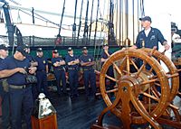 US Navy 050823-N-9076B-001 Electrician's Mate 1st Class Aaron Walker speaks to chief petty officer selectees as he stands at the helm of USS Constitution in Boston