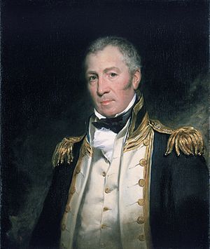 Portrait of middle-aged man with serious expression, in early 19th century naval uniform – dark jacket with gold embroidery and heavy shoulder decorations, white waistcoat and shirt with a high collar and black bow. His head is tilted slightly to left.