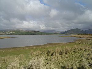 A view of Broad Water with grass in the foreground leading down to the shore , and hills in the background behind the lake.