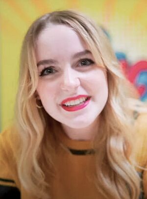 McKenna Grace smiling while wearing a yellow shirt at the 2023 German Comic Con, in Dortmund