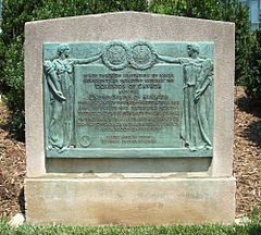 Bronze plaque containing two human figures holding the seal of the United States and the coat of arms of Great Britain with a description of the treaty in between them.