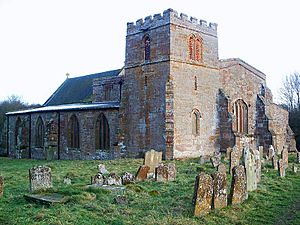 A stone church seen from the northwest with a squat tower in the foreground, with the north aisle to the left and the west end of the nave to the right