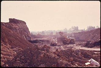 COAL COMPANY EQUIPMENT IS USED TO LOAD TRUCKS AT A STRIP MINING SITE WEST OF BARNESVILLE, OHIO, IN THE SOUTHEASTERN... - NARA - 555638