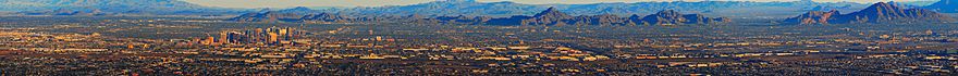 aerial view of the Phoenix skyline, showing the tall buildings of downtown Phoenix to the left of the photo, mountains in the background, the flatness of the rest of the city, with Sky Harbor airport