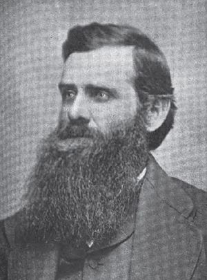 A man with dark hair and a bushy, dark beard
