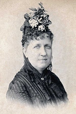 Head and shoulders photograph of a middle-aged Isabel wearing a flower hat