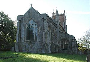 A stone church see from the east showing a Perpendicular style east window, and beyond, a battlemented tower