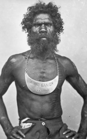 Man wearing breastplate inscribed King Sandy Brisbane 