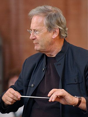 Grey-haired man holding conductor's baton in both hands