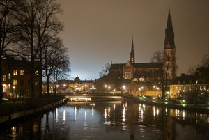 Uppsala Cathedral in background of the Fyris river at night.