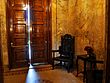 A marble-walled room with a chair and wooden door