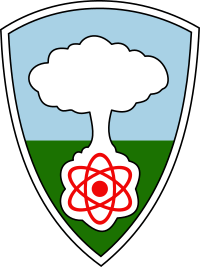  A shield with a white mushroom cloud rising from a red atom against a blue sky