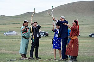 Archers in Traditional Mongolian Outfits Guide Secretary Kerry as He Prepares to Shoot an Arrow at a "Mini-Nadaam" Outside Ulaanbaatar (27443915682)
